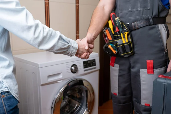 Close-up of a repairman shaking hands with a female customer. Male repairman for washing machine repair — Stock Photo, Image