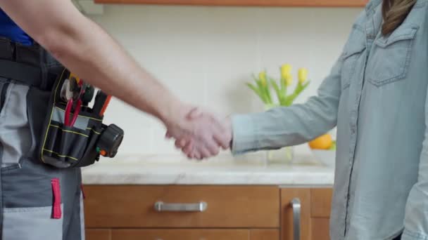 Close up de encanador e cliente apertando as mãos na cozinha. Reparador apertando as mãos com a mulher — Vídeo de Stock