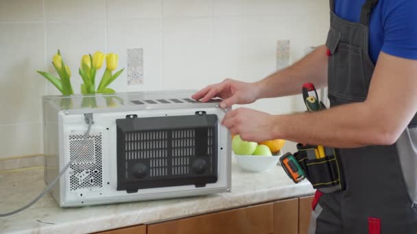 Jovem reparador de fixação e reparação de forno de microondas por chave de fenda na cozinha — Vídeo de Stock