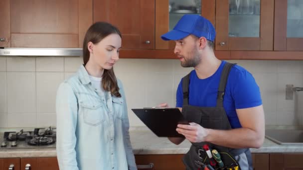 Zákaznice podepisující fakturu od muže instalatéra stojící v kuchyni — Stock video