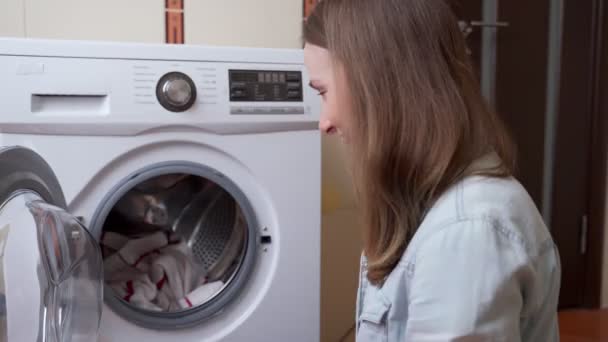Giovane donna che mette il bucato in lavatrice. Lavanderia donna con moderna macchina automatica — Video Stock