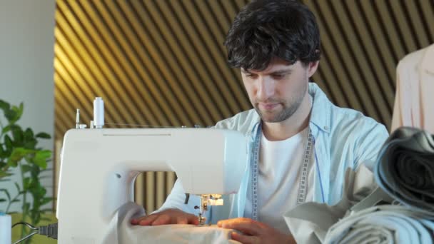 Modieuze kledingontwerper naait aan een naaimachine. Modeontwerper werkt in zijn atelier — Stockvideo