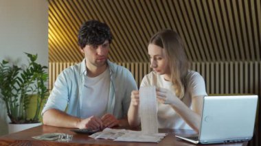 Genç bir aile evde evrak işleriyle uğraşıyor. Genç çift, masada kocasıyla birlikte bir sürü evrak, dizüstü bilgisayar, hesap makinesi ve fatura ile oturmuş endişeli görünüyor.