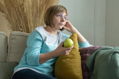 Elinde yeşil elma tutan yaşlı bir kadın, sağlıklı beslenme konsepti.