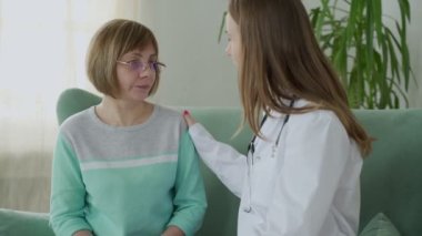 Doktor evde yaşlı bir kadını ziyaret ediyor. Kadın doktor ev ziyareti sırasında yaşlı kadını teselli ediyor.