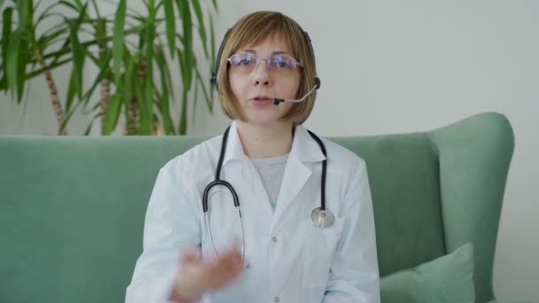 Terapeuta médica anciana que usa videollamada de auriculares hablando con la cámara web consultando al paciente virtual en línea — Vídeo de stock