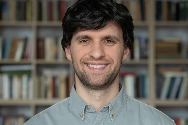 Man student standing in university library and looking into camera