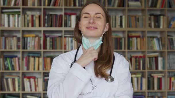 女医生在书架上摘下医用面罩. — 图库视频影像