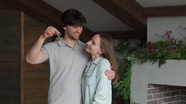 Feliz joven pareja orgullosamente mostrando las llaves de su nueva casa — Vídeos de Stock