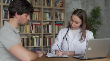 Bir erkek, test sonuçlarını gösteren bir kadın doktoru dinler.