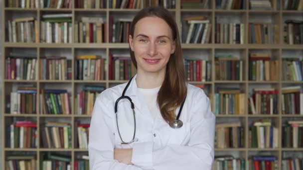 Die junge Ärztin in einer Bibliothek lächelt glücklich. Konzept medizinischer Versorgung und Wohlfahrt — Stockvideo