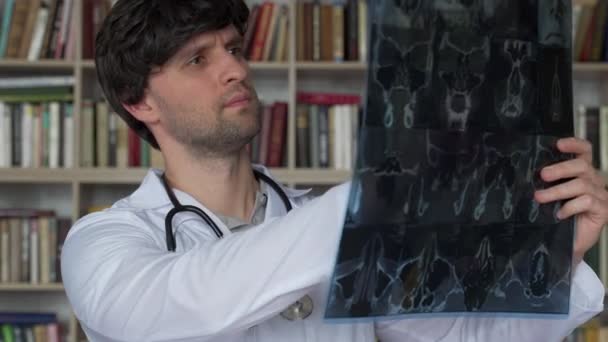 Erkek doktor klinikte bir hastanın röntgenine bakıyor. — Stok video