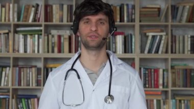 Tele sağlık danışmanlığı sırasında kameraya konuşan kulaklıklı adam. Klinikte görüntülü konuşma kullanan bir doktor.