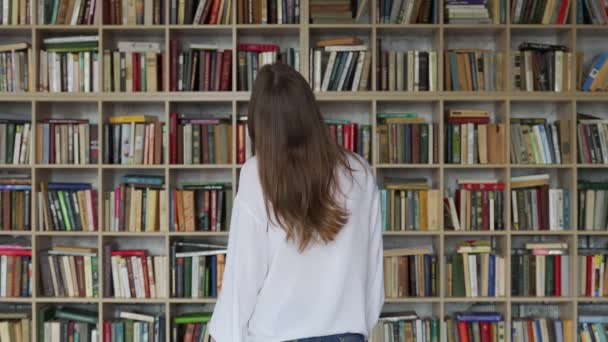 Młoda studentka czyta książkę w bibliotece — Wideo stockowe