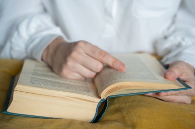 Kütüphanede kitap okuyan yakın plan bir kadın öğrenci.