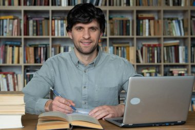 Üniversite kütüphanesinde dizüstü bilgisayar kullanan erkek öğrenci