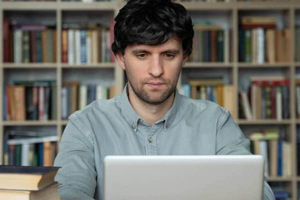 Estudiante masculino usando laptop estudiando en la biblioteca universitaria — Foto de Stock