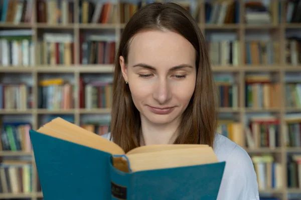 Estudiante joven leyendo un libro en una biblioteca — Foto de Stock