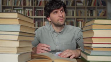 Adam kütüphanede masa başında çalışıyor, harika bir fikri var, parmağını kaldırıyor..