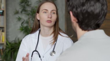 Kadın doktor, erkek bir hastayla koltukta otururken konuşuyor.