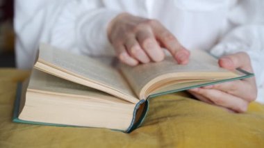 Kütüphanede kitap okuyan yakın plan bir kadın öğrenci.