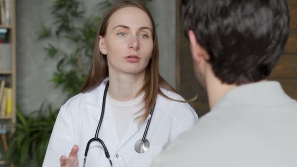 Kadın doktor, erkek bir hastayla koltukta otururken konuşuyor. — Stok video