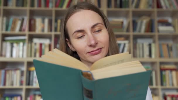 Ung kvindelig studerende læser en bog i et bibliotek – Stock-video