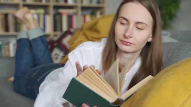 Gros plan femme couchée sur un canapé confortable et la lecture d'un livre passionnant — Video