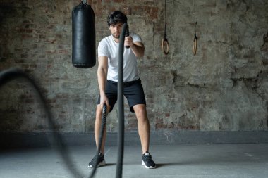İşlevsel spor salonunda iple güçlü bir adam eğitimi. Spor salonundaki antrenman sırasında Crossfit halat egzersizi.