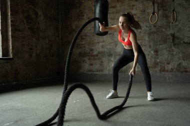 Spor salonunda spor yapan formda genç bir bayan. Spor salonunda savaş halatlarıyla egzersiz yapan bir kadın.