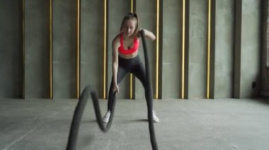 Spor salonunda halat egzersizi yapan bir kadın. Sporcu kadın spor salonunda çalışıyor.