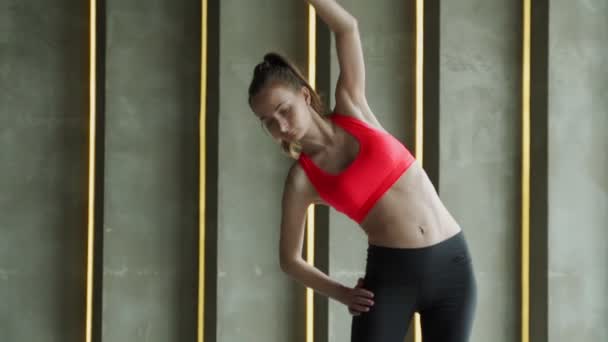 Atletická mladá žena ve sportovním oblečení zahřívá protahování Arms stojí v moderní tělocvičně. Mladý krásný atletický žena v legíny a top dělá strečink cvičení. — Stock video