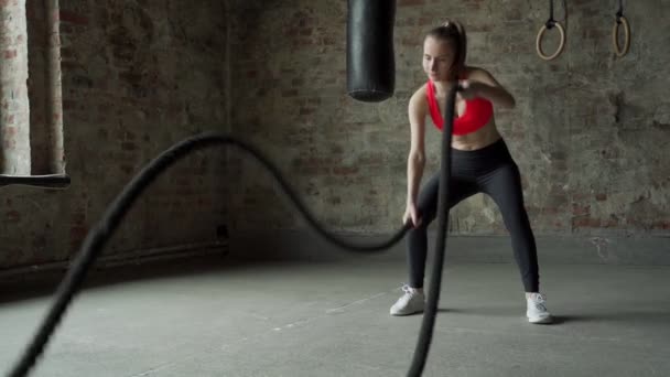 Młoda wysportowana kobieta ćwicząca na siłowni. Kobieta ćwiczy z linami bojowymi na siłowni — Wideo stockowe