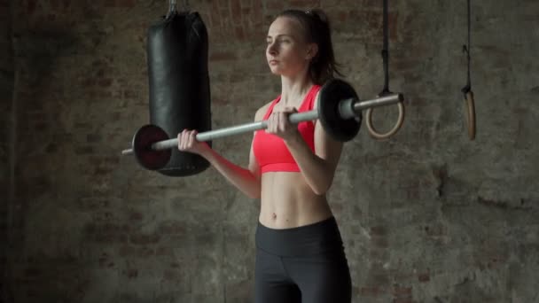 Młoda kobieta podnosi sztangę robiąc bicepsy na siłowni. Fitness trening kobiet na siłowni — Wideo stockowe