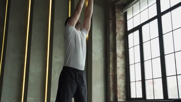 Atletisk man lyfter en kettlebell över huvudet under ett träningspass på gymmet — Stockvideo