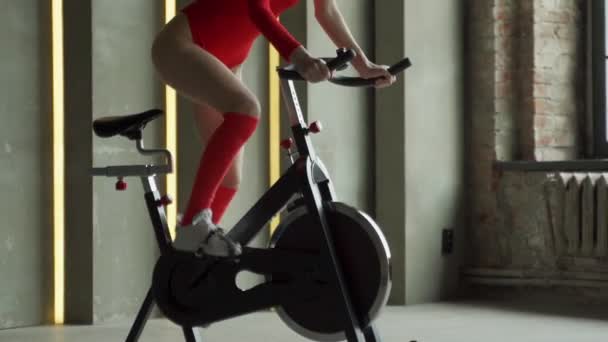 Atletická žena v červené kombinéze dělá aerobní kolo cvičení v posilovně — Stock video