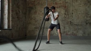 İşlevsel spor salonunda iple güçlü bir adam eğitimi. Spor salonundaki antrenman sırasında Crossfit halat egzersizi.