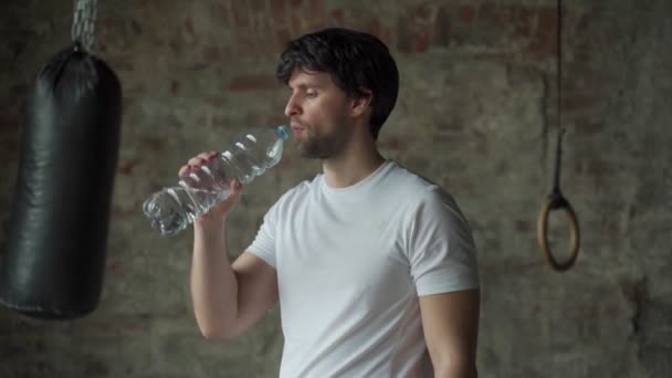 De man drinkt water uit de fles in de sportschool. Gezondheidszorg en training. — Stockvideo