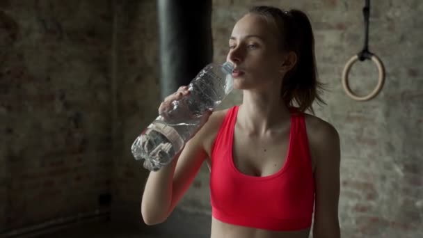 Mulher bebendo água no ginásio após o treino. Mulher no ginásio fazendo uma pausa do treino. — Vídeo de Stock