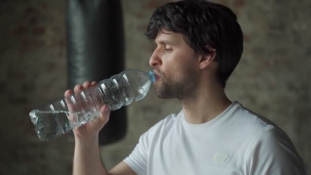 Man drinks water from bottle in gym. Health care and workout. — Stock Video