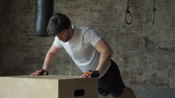 En man som tränar på gymmet gör armhävningar från en trälåda — Stockvideo
