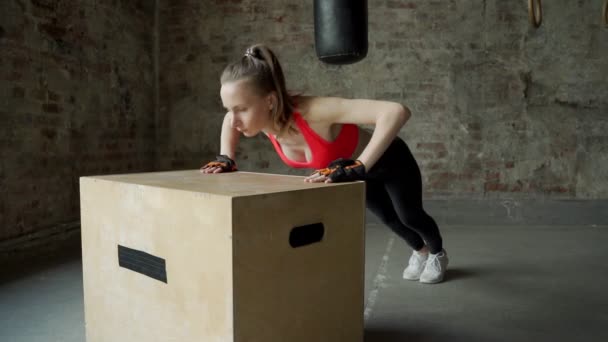 Sportowiec młoda kobieta robi pompki na drewnianym pudełku w siłowni — Wideo stockowe