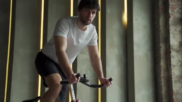 젊은 체력 남자가 체육 시간에 자전거로 심장 심장외과 훈련을 받고 있습니다. 남자가 운동하면서 자전거돌리기를 하는 남자 — 비디오