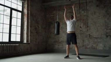 Sporcu adam jimnastik salonunda tıbbi top fırlatıyor.
