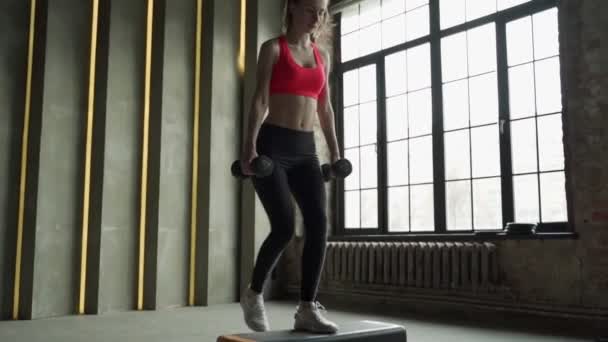 Femme sportive pratique sur la plate-forme étape dans la salle de gym. Jeune femme faisant de l'exercice avec plate-forme étape en gym — Video