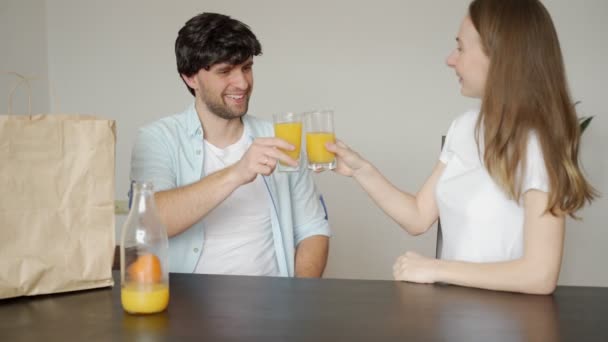 Pareja sonriente bebiendo zumo de naranja fresco disfrutando de una agradable cocina matutina juntos, comida saludable y concepto de estilo de vida — Vídeos de Stock