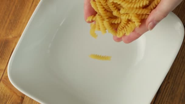 Γυναικεία χέρια χύνουν ζυμαρικά σε ένα πιάτο — Αρχείο Βίντεο