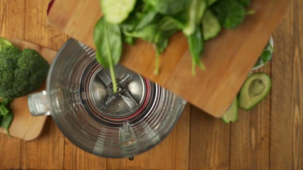 Close-up of a womans hands adding sliced vegetables to a blender in the kitchen. Top view — Vídeo de Stock
