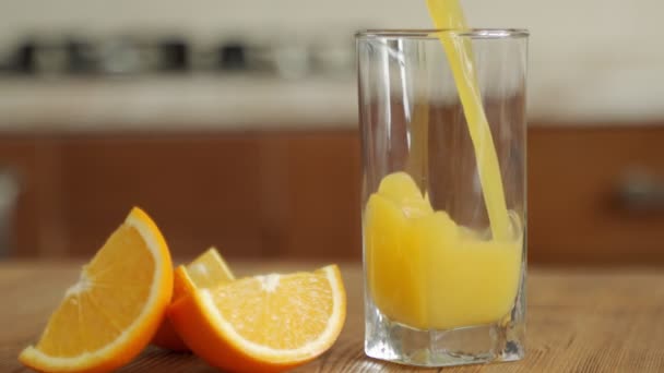 橙汁倒入放在木制桌子上的杯子里 — 图库视频影像