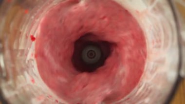 Close up fresh strawberry smoothie mixed in a blender, slow motion, top view